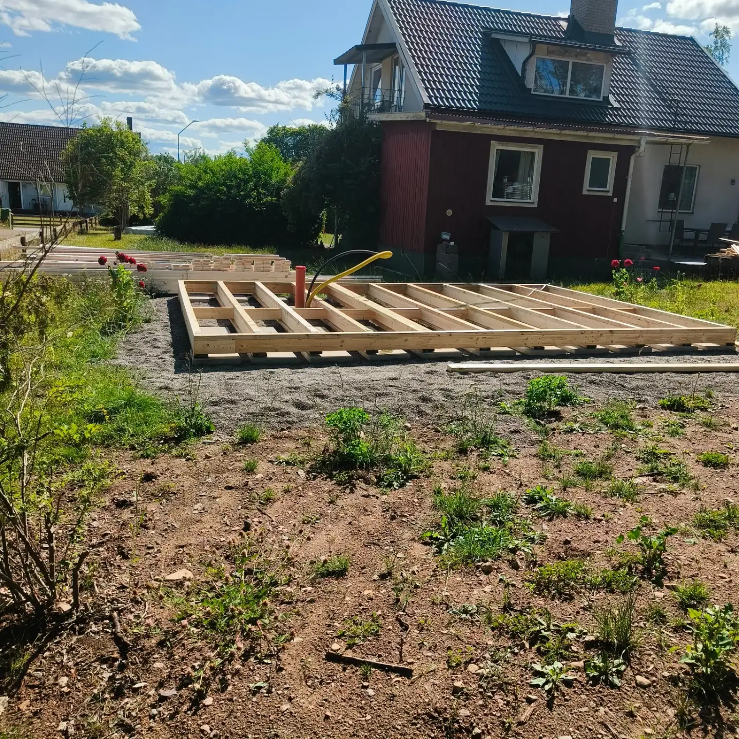 Syll och bjälklag på grusgrund framför falurött hus