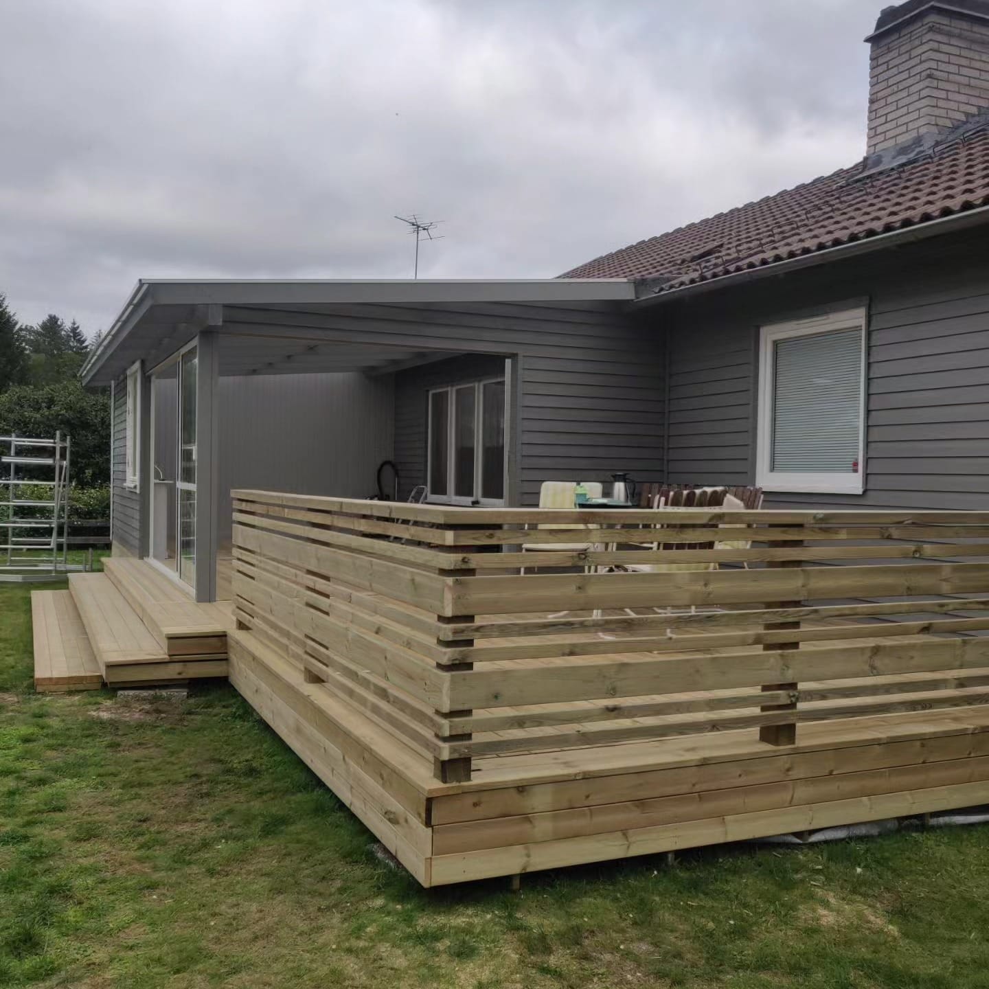 Trädäck med horisontellt räcke mot villa