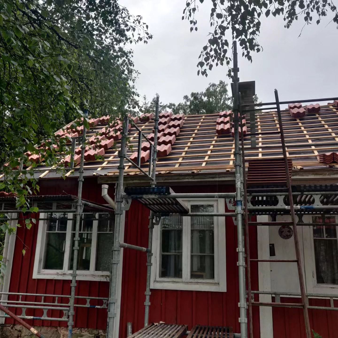 Falurött hus med ställning och nytt takunderlag inför läggning av tegelpannor
